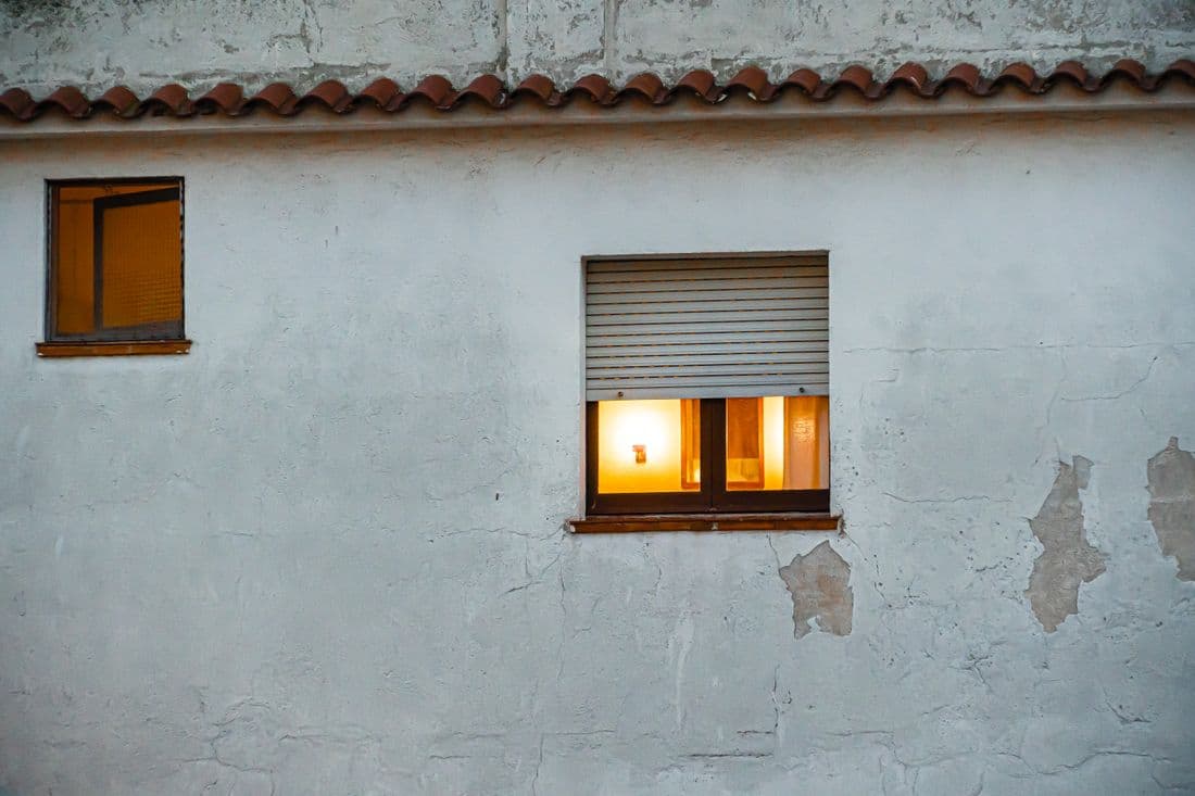 Muro esterno con intonaco che si distacca nella parte bassa, coppi e tapparella